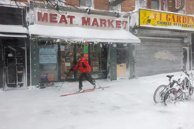 A man skis past shopfronts in Brooklyn.