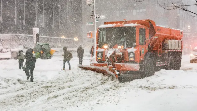 A snow plough vehicle clears snow on a street as snow falls during a winter storm in New York City