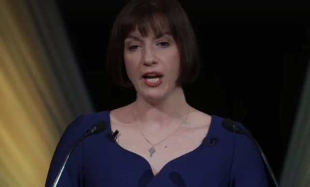 Education Secretary Bridget Phillipson wearing a blue top while speaking against a black and gold background.