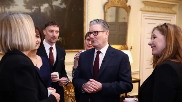 Starmer speaks to a woman while four people around them listen
