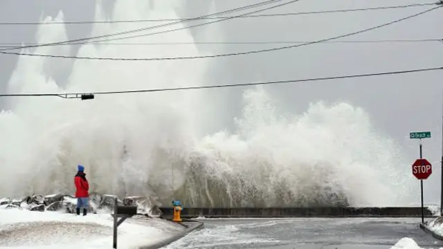 Huge waves crash on a snowy beach in Maine