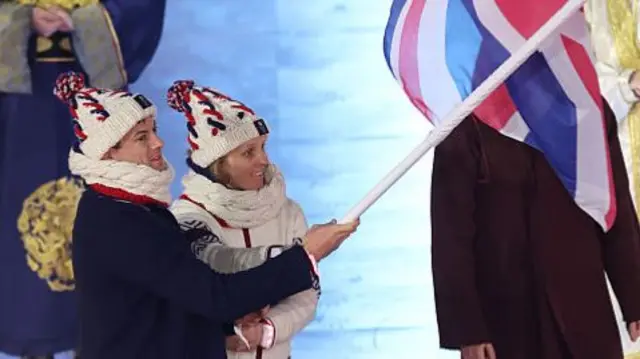 Matt Weston and Charlotte Bankes fly the British flag at the closing ceremony