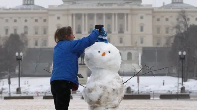 Ann Eaton, visiting from Kennebunk, Maine, builds a snowman near the Capitol in Washington DC, US, 23 February 2026.