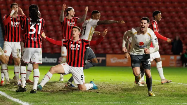 Walsall players have their arms in the air as Jon Mellish runs off to celebrate