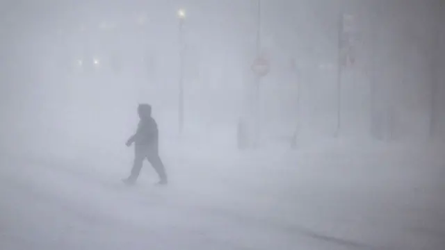 People walk through whiteout conditions on February 23, 2026 in Boston, Massachusetts.