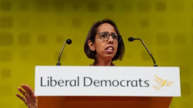 Munira Wilson speaking in front of a Liberal Democrats podium