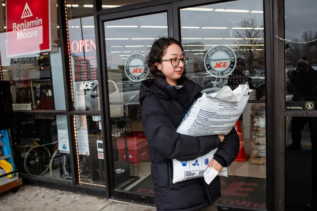 A woman carries a bag of rock salt she purchased from a hardware store ahead of a winter storm in Boston, Massachusetts on February 22, 2026.