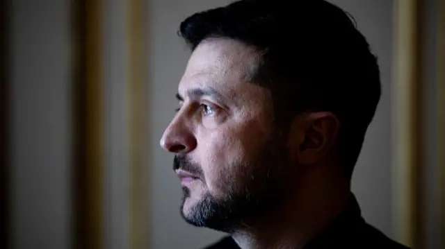 Zelensky looks to the side in a close up portrait of his head and shoulders