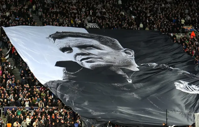 Fans hold up a tifo of Newcastle United manager Eddie How