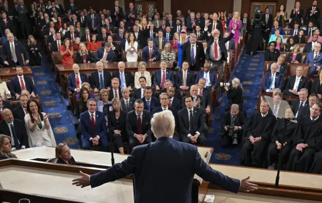Donald Trump, arms outstretched, stands in front of a joint session of Congress