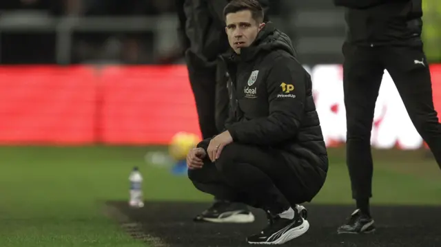 A kneeling West Brom boss Eric Ramsay