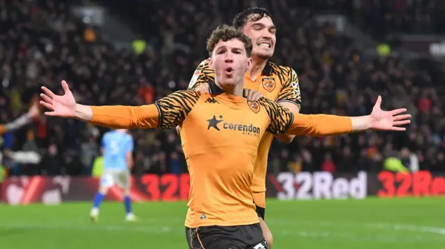 Lewis Koumas has his arms outstretched in celebration