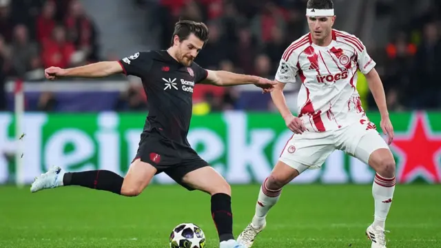 Jonas Hofmann of Bayer 04 Leverkusen crosses the ball whilst under pressure from Lorenzo Pirola of Olympiacos FC during the UEFA Champions League 2025/26 League Knockout Play-off Second Leg match between Bayer 04 Leverkusen and Olympiacos FC at BayArena