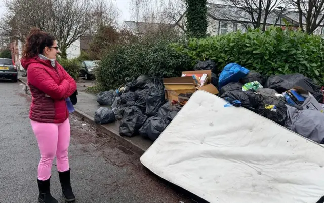 A Brookfield Road resident looks at the pile of rubbish gathering on her road