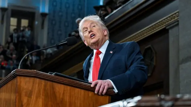 Donald Trump speaking into a microphone and turnning his head