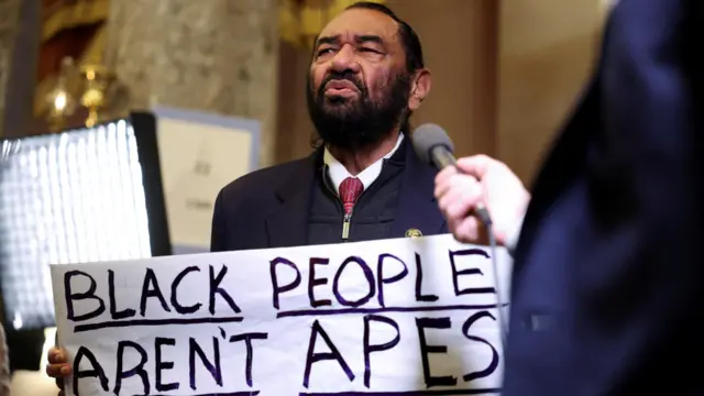 Rep Al Green holds a sign that reads "Black people aren't apes".