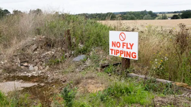 A sign by a field saying no fly tipping.