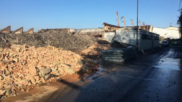 Bricks and rubble dumped at a site in Margate, Kent, adjacent to a road. There is blue sky and a single-storey building.