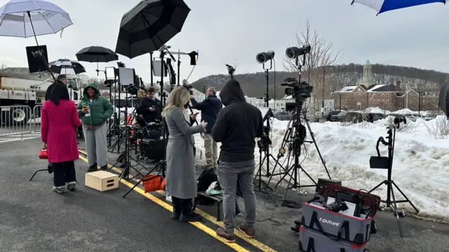 scene of reporters lined up on a street with their filming gear
