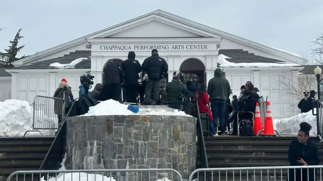 image of the front of the Chappaqua Performing Arts Center, with snow on the ground and reporters out front