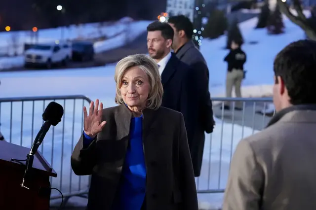 Hillary Clinton waves while turning away from a lectern