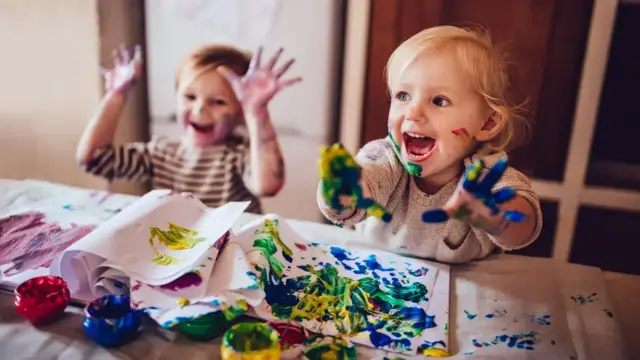 Two young children paint themselves