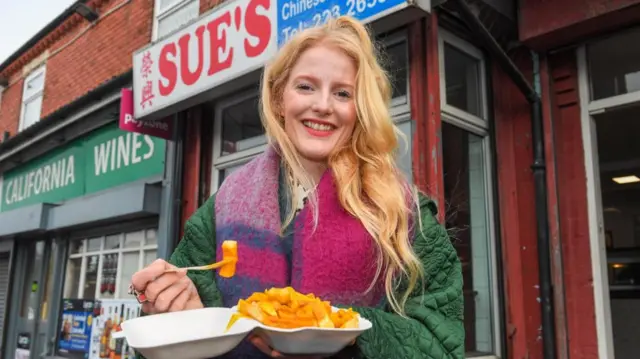 Newly-elected Green MP for Gorton and Denton, Hannah Spencer, eats chips in curry sauce from a takeaway near her constituency office in Manchester.