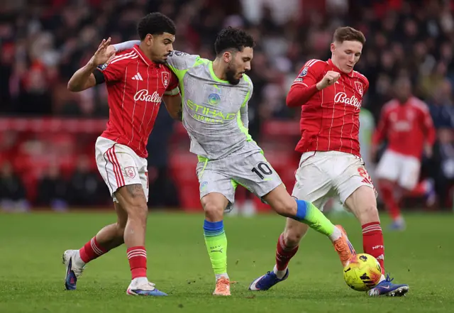Morgan Gibbs-White and Elliot Anderson of Nottingham Forest tackle Rayan Cherki of Manchester City during the Premier League match between Nottingham Forest and Manchester City