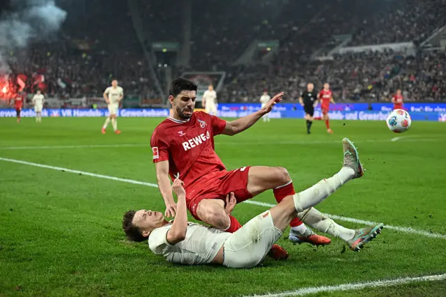 Cenk Oezkacar of 1. FC Koln is tackled by Robin Fellhauer of FC Augsburg