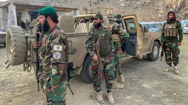 Afghan soldiers in full battle gear standing beside a military truck