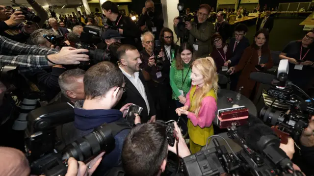 Spencer and Polanski surrounded by cameras