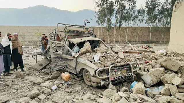 A group of men in Afghanistan examining the ruins of a vehicle hit by Pakistani air strikes