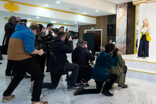 Photographers take pictures of Hannah Spencer on stage