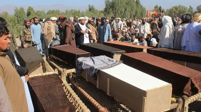 Coffins lined on a road surrounded by men