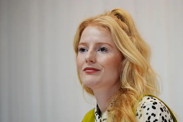 Newly-elected Green MP Hannah Spencer at a public event following her win. She's wearing a green vest and dalmatian black dots style shirt