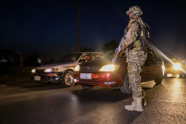A Taliban security checks a vehicle at a checkpoint in Kabul, Afghanistan