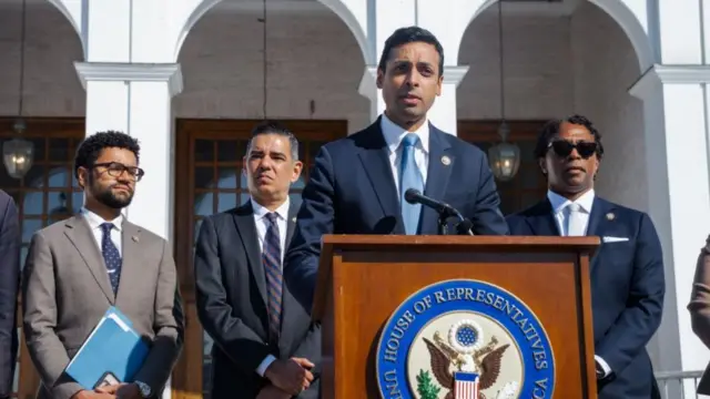 Subramanyam at a podium flanked by other Democrats