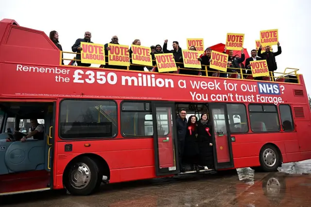 Mayor of Greater Manchester Andy Burnham, Labour party candidate Angeliki Stogia (C) and Britain's Deputy Leader of the Labour Party Lucy Powell (R) pose on a campaign bus in Manchester on February 26, 2026, ahead of the crucial Gorton and Denton by-election. A sign on the bus says: Remember the £350 miullion a week for our NHS? You can't trust Farage.