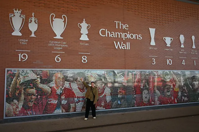 A fans poses beside The Champions Wall ahead of the English Premier League football match
