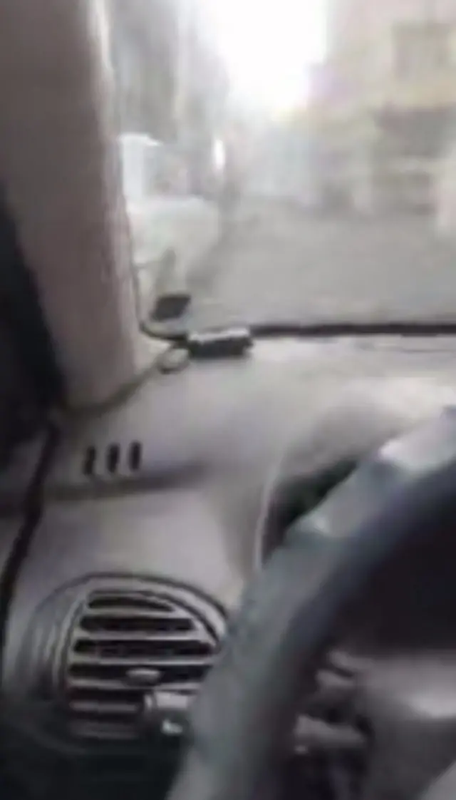 The driver's seat view of a car driving along an Iranian road