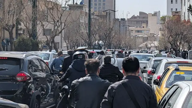 Iranians try to clear a street amid heavy traffic in Tehran, Iran.