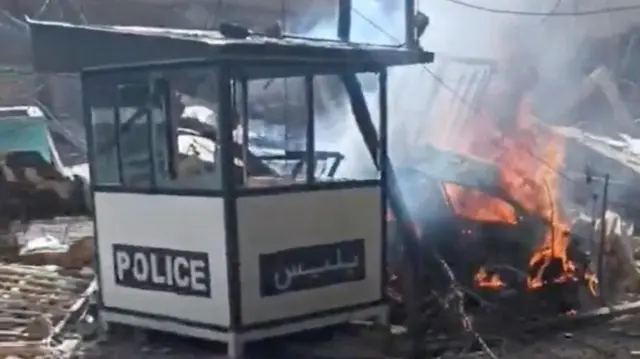 Flames rise in an area in Tehran, as a small structure that says police lies empty in Iran