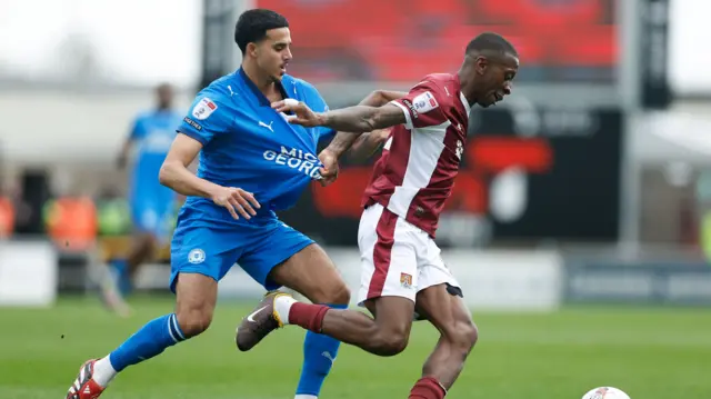 Tyrese Fornah of Northampton Town and Brandon Khela of Peterborough United compete for the ball