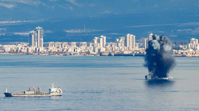 A projectile explodes over the water in the bay of Haifa off the coast of northern Israel