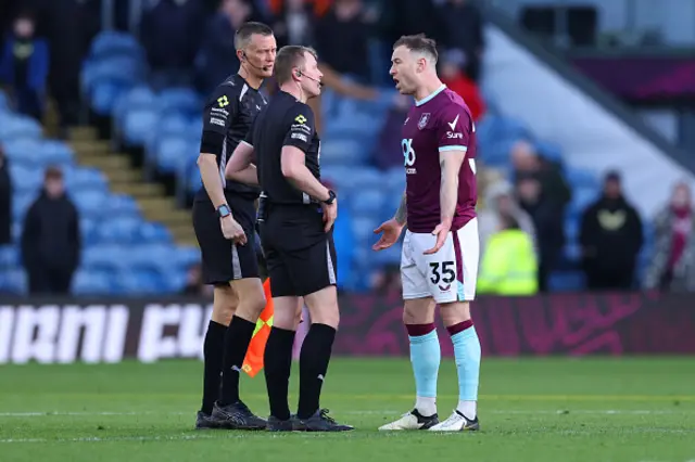 Referee Samuel Barrott talks with Ashley Barnes