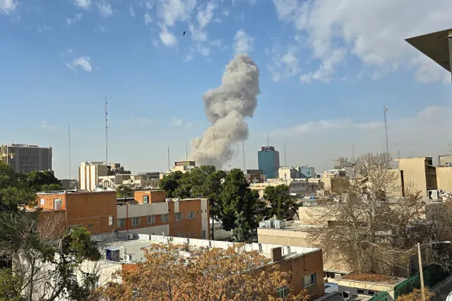 A plume of smoke rises over urban rooftops in Tehran.