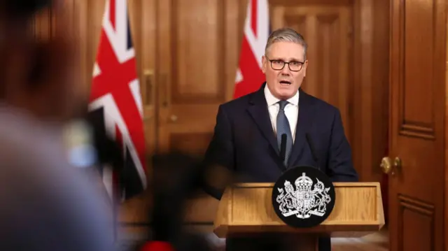 Keir Starmer mid-speech in a wood-panelled room in No10
