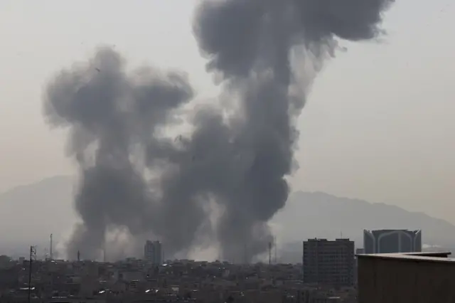 Plumes of smoke rise over the Tehran cityspace