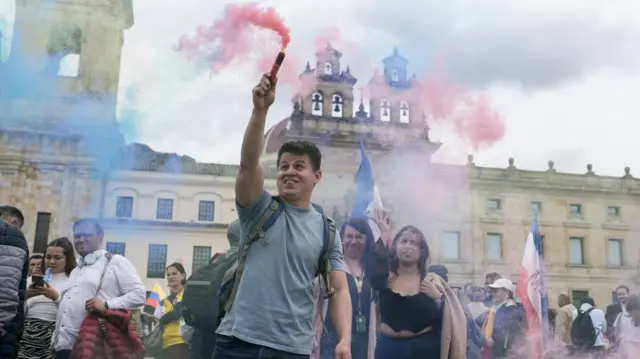 राष्ट्रपति गुस्तावो पेत्रो के समर्थन में कोलंबियाई सरकार द्वारा बुलाई गई रैली के लिए इकट्ठा हुए लोगों के बीच एक व्यक्ति ने धुएं का गुबार उठा रखा था।