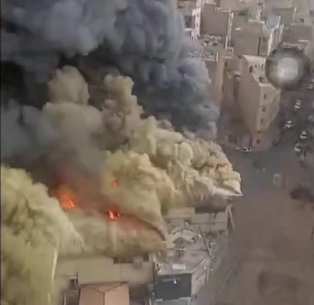A screengrab from a video taken from above the market showing a large fire and a think cloud of black and brown smoke
